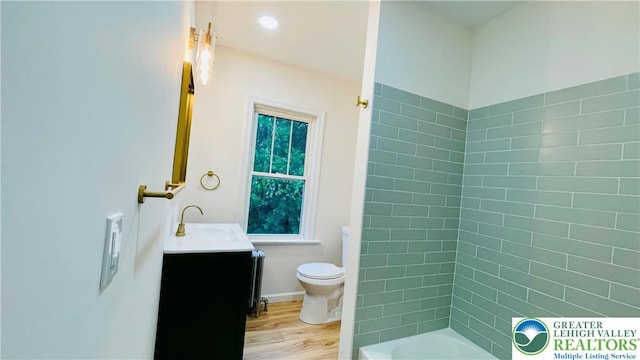 full bath with wood finished floors, toilet, vanity, and radiator
