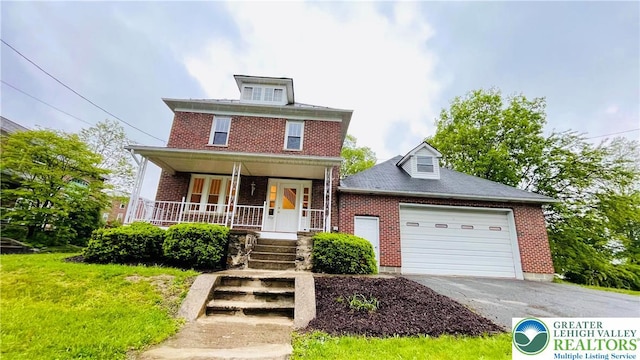 american foursquare style home with brick siding, asphalt driveway, a garage, and covered porch