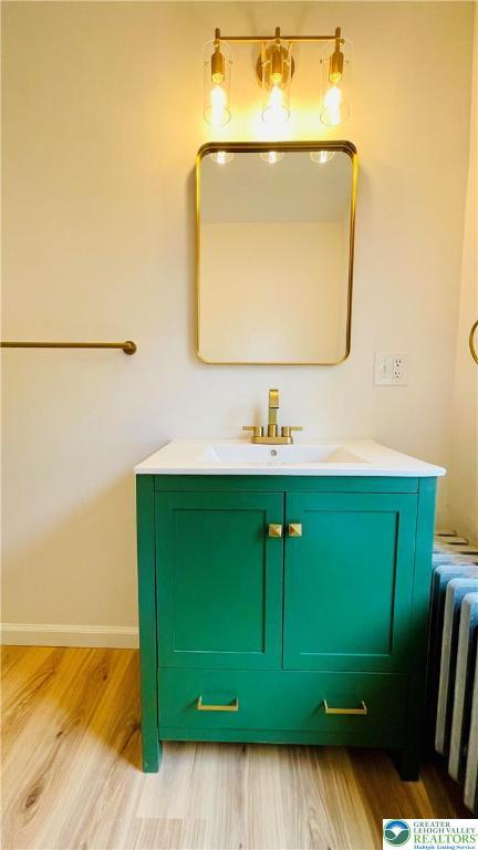 bathroom with wood finished floors, vanity, radiator heating unit, and baseboards