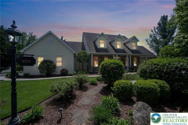 cape cod-style house featuring a lawn