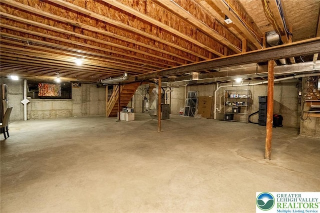 unfinished basement featuring heating unit and stairs