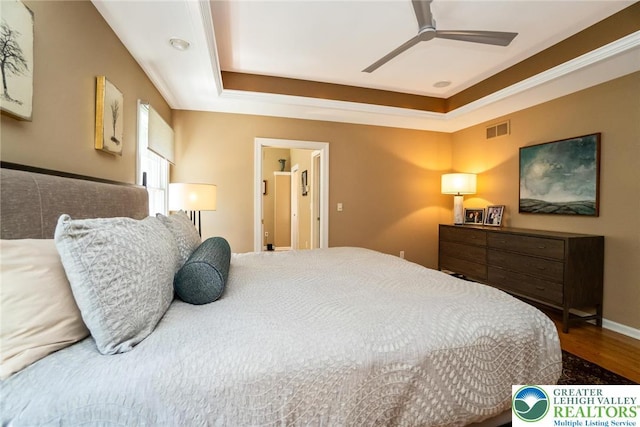 bedroom featuring a raised ceiling, wood finished floors, and a ceiling fan