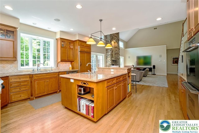 kitchen featuring a sink, light wood finished floors, open floor plan, tasteful backsplash, and recessed lighting