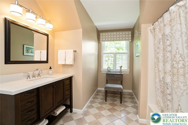 bathroom featuring vaulted ceiling, vanity, baseboards, a shower with shower curtain, and tile patterned floors