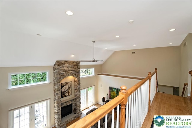 corridor with an upstairs landing, wood finished floors, recessed lighting, and high vaulted ceiling