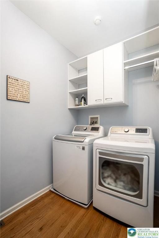 laundry area featuring independent washer and dryer, wood finished floors, cabinet space, and baseboards