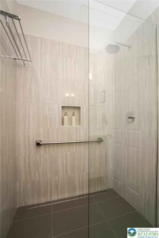 full bathroom with tiled shower and tile patterned flooring
