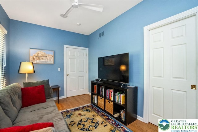 living room with ceiling fan, wood finished floors, and baseboards