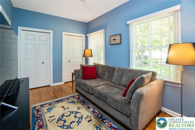 living area with wood finished floors, baseboards, and ceiling fan