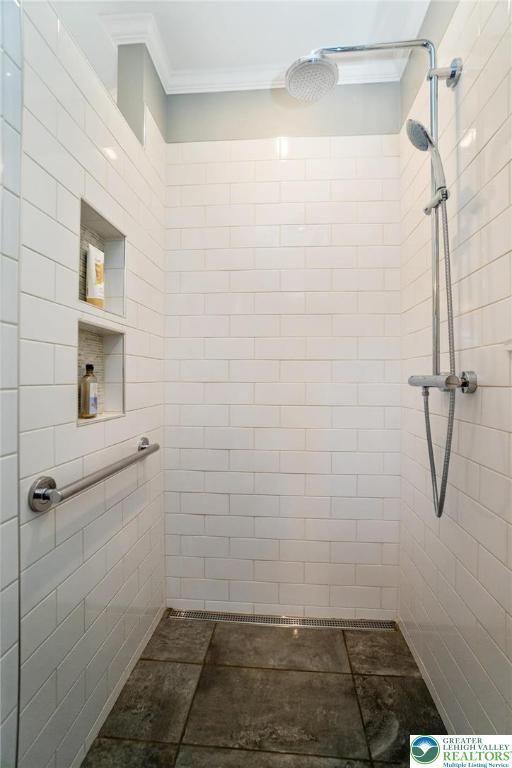 bathroom with crown molding and a tile shower