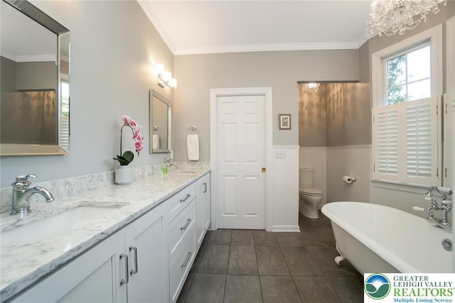 full bathroom featuring ornamental molding, a freestanding tub, double vanity, tile patterned floors, and toilet