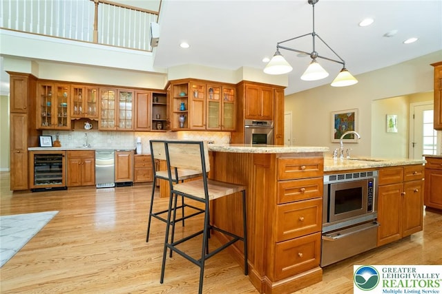 kitchen featuring a sink, wine cooler, brown cabinetry, appliances with stainless steel finishes, and recessed lighting