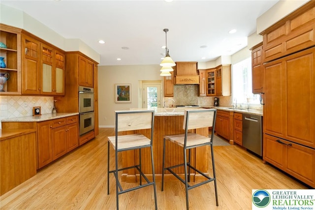 kitchen featuring appliances with stainless steel finishes, a sink, light wood-style floors, backsplash, and recessed lighting