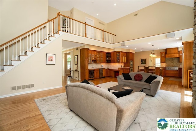 living area featuring a high ceiling, light wood-style flooring, stairway, and recessed lighting