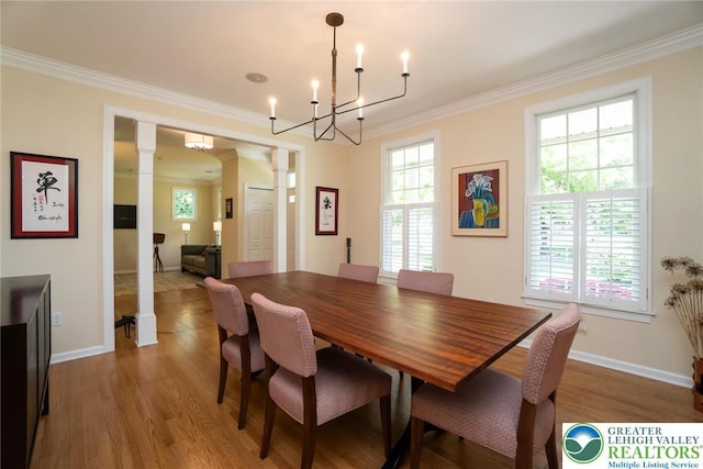 dining room featuring decorative columns, ornamental molding, a chandelier, wood finished floors, and baseboards