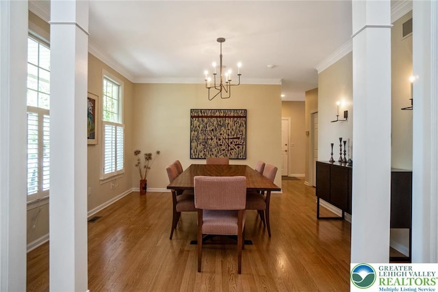 dining area featuring a chandelier, wood finished floors, crown molding, baseboards, and ornate columns