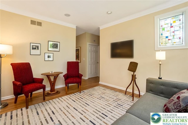 living area with crown molding, wood finished floors, and baseboards