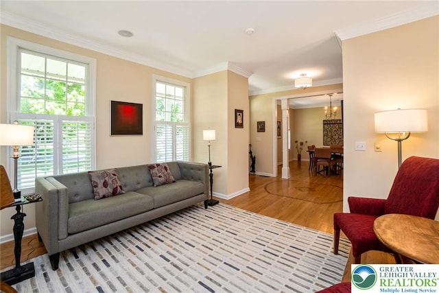 living room with light wood-type flooring, crown molding, baseboards, and a chandelier