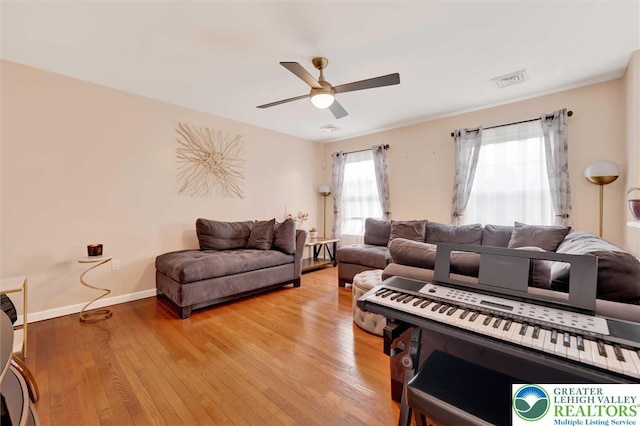 living room with ceiling fan, light wood-style floors, and baseboards