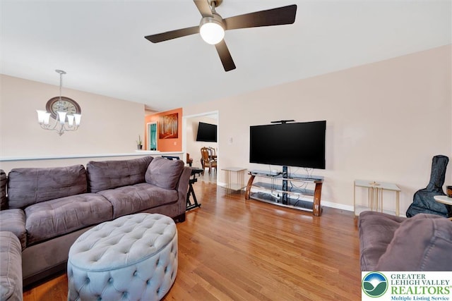 living area with a chandelier, light wood-style flooring, a ceiling fan, and baseboards