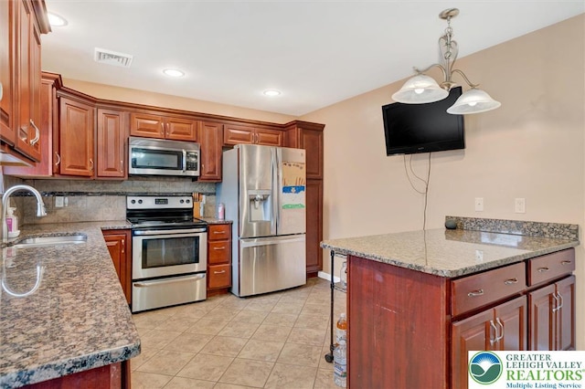 kitchen featuring appliances with stainless steel finishes, a sink, decorative backsplash, light tile patterned flooring, and pendant lighting