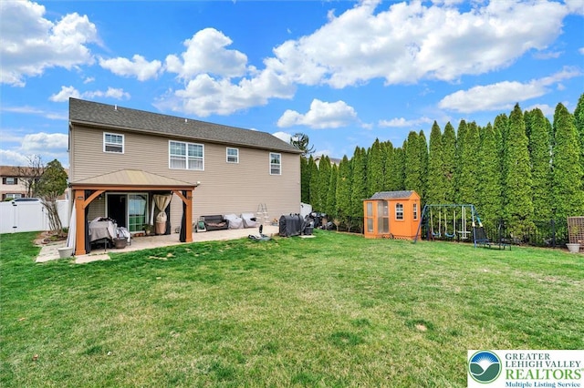 back of house featuring a patio area, a gazebo, a playground, and an outbuilding