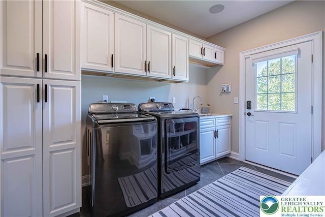 washroom featuring washing machine and dryer, cabinet space, and dark tile patterned floors