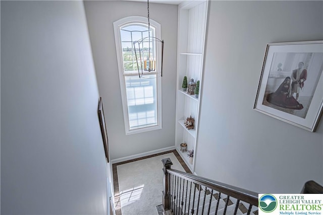 stairway with a chandelier, baseboards, and carpet floors