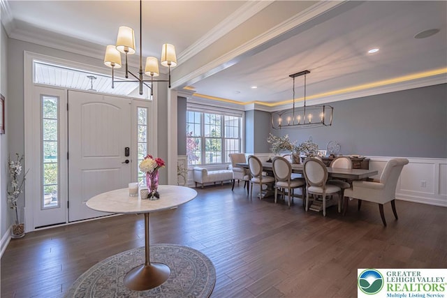 foyer with a chandelier, dark wood-style flooring, crown molding, wainscoting, and a decorative wall