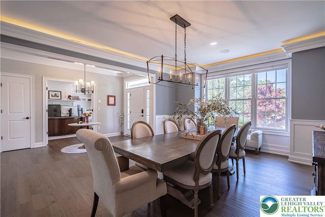 dining room featuring a chandelier, dark wood-type flooring, crown molding, and wainscoting