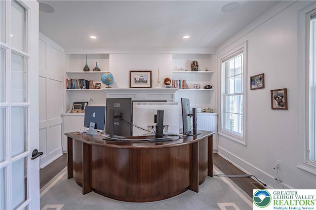 home office with plenty of natural light, wood finished floors, built in features, and baseboards
