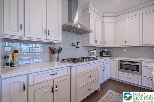 kitchen with wall chimney exhaust hood, stainless steel gas cooktop, white cabinetry, and dark wood-style flooring