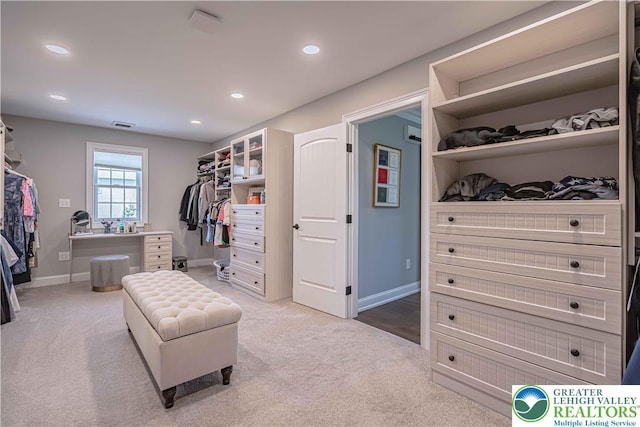 walk in closet with light colored carpet