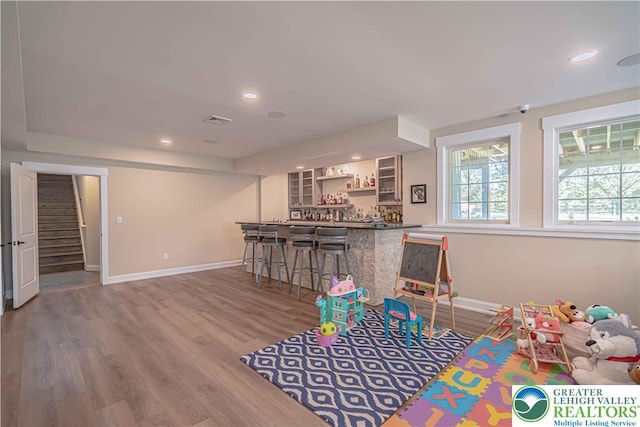 recreation room featuring a dry bar, baseboards, wood finished floors, and recessed lighting