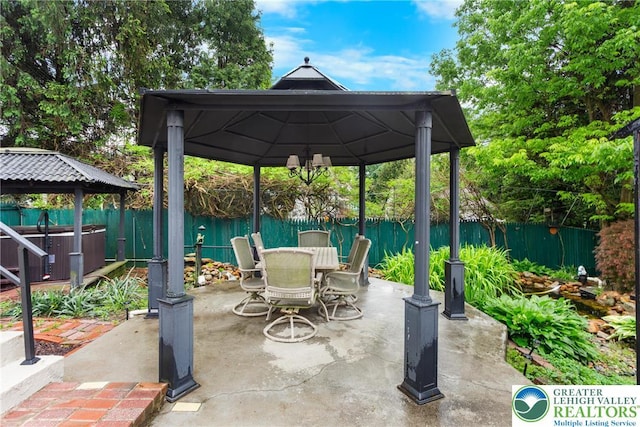 view of patio featuring a gazebo, fence, a hot tub, and outdoor dining space