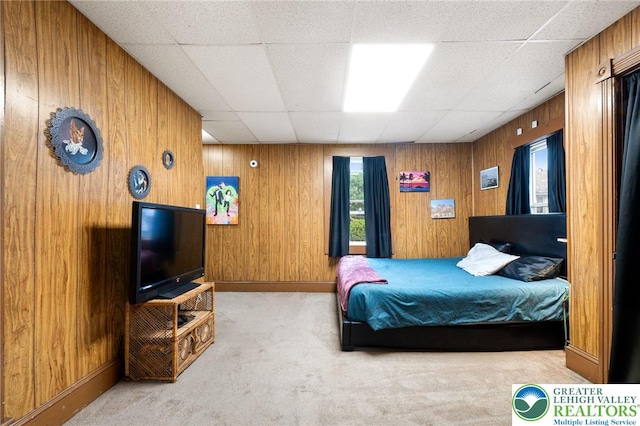 bedroom featuring carpet floors, a drop ceiling, wooden walls, and baseboards