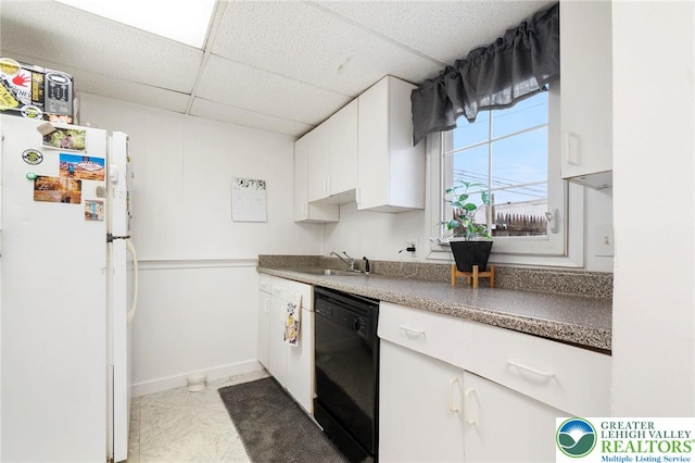 kitchen with freestanding refrigerator, black dishwasher, a sink, white cabinets, and a drop ceiling