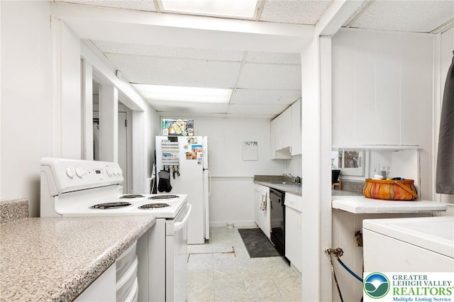 kitchen with white appliances, white cabinets, a drop ceiling, light countertops, and a sink