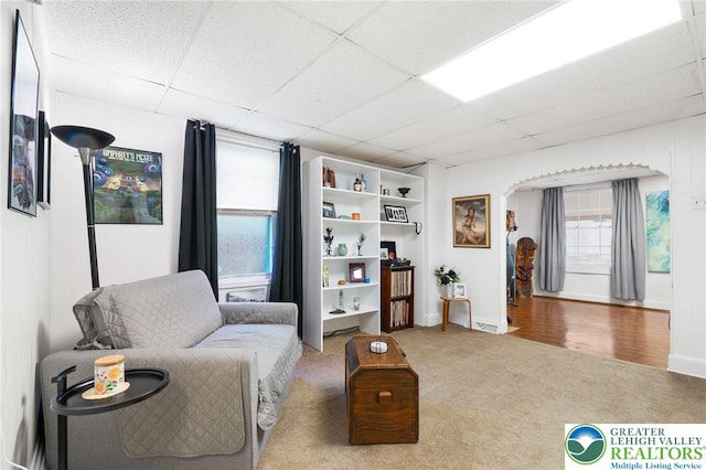 sitting room with a paneled ceiling, carpet, and baseboards