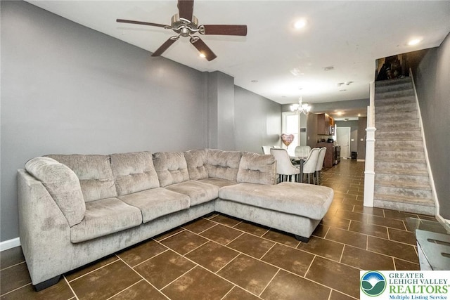 living room featuring stairs, a ceiling fan, a chandelier, dark tile patterned floors, and baseboards