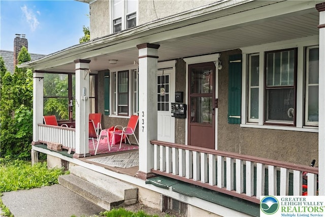 view of exterior entry with covered porch and stucco siding