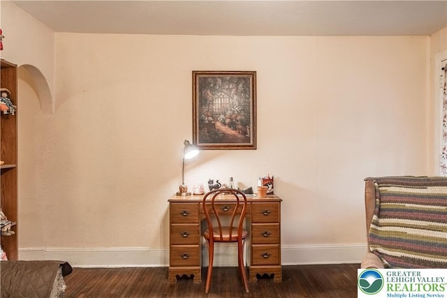 office with arched walkways, dark wood finished floors, and baseboards