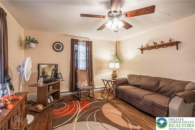 living room with wood finished floors, ceiling fan, a baseboard heating unit, and baseboards