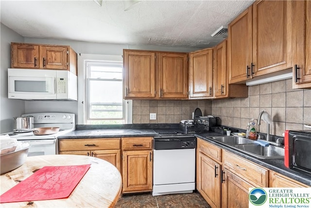 kitchen featuring white appliances, a sink, decorative backsplash, dark countertops, and brown cabinetry