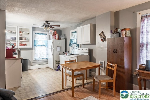 kitchen with a ceiling fan, white appliances, a textured ceiling, white cabinetry, and light floors