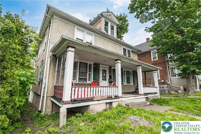 american foursquare style home with a porch and stucco siding
