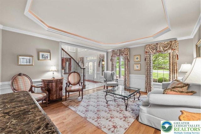 217 Rising Meadow Way, Middle Smithfield Twp, PA 18302 - living room featuring a tray ceiling, crown molding, wainscoting, wood finished floors, and stairs