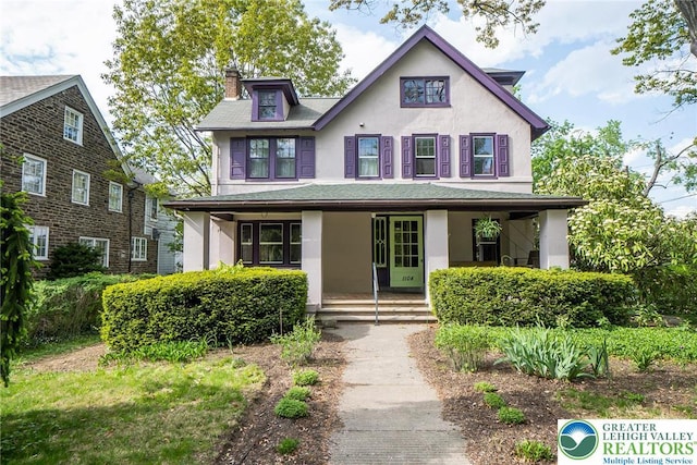 view of front of property featuring covered porch, stucco siding, and a chimney