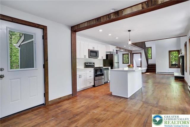 8210 Pine Grove, Stroud Twp, PA 18301 - kitchen featuring stainless steel appliances, white cabinetry, light wood finished floors, decorative backsplash, and light countertops