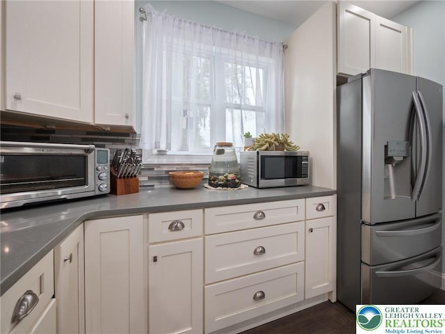 kitchen featuring appliances with stainless steel finishes, white cabinetry, backsplash, and dark wood finished floors